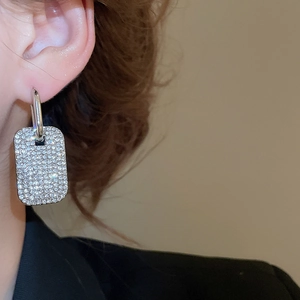 Primo piano di orecchini rettangolari in argento con cristalli pavé indossati da una modella