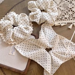 Detailed view of white polka dot scrunchie set with lace edges and ribbon on a table