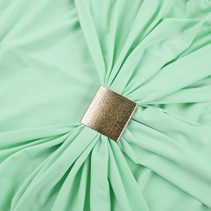 Détail de la boucle carrée dorée sur le tissu plissé vert menthe de la robe longue