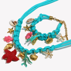 Detail of nautical jewelry set with blue woven rope, sea shell pendants, and gold hardware