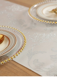 Elegant round jute placemat with silver pattern on wood table with gold utensils