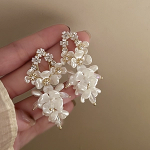 Detailed close-up of tiered white shell flower earrings with shimmering resin petals