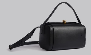 Vue latérale du sac boîte noir avec fermoir doré en métal et détail de la poignée
