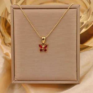 Macro shot of 18K gold butterfly necklace featuring four sparkling red zircon gemstones
