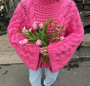 Detailed close-up of chunky knit texture on a bright pink oversized round neck sweater