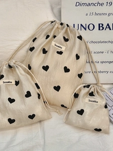 Three sizes of cream drawstring storage bags with black hearts and ribbon ties