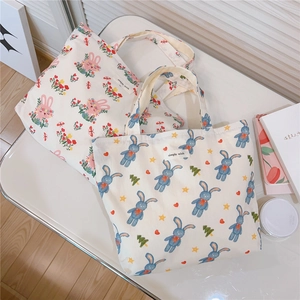 Detail of pink and blue rabbit printed cotton handbags with simple wish label on table
