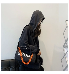 Détail du sac bandoulière en nylon noir avec chaîne orange et inscription SPORT blanche