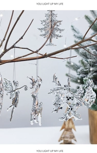 Close-up of silver Christmas ornaments with reindeer and leaf shapes on festive branches