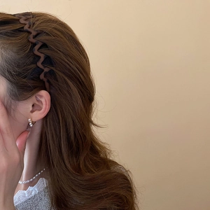 Brown wavy leopard pattern headband worn by a model with elegant pearl jewelry details