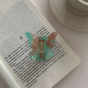 Detailed view of an acetate butterfly hair claw clip with pink and green gradient finish