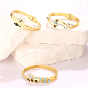 Macro detail of gold snake bracelet with zircon eyes and enamel on stone display