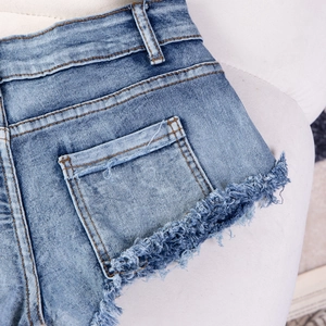 Detail von retro-gewaschenen blauen Denim-Shorts mit Fransen und Vintage-Quastenbesatz