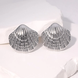 Minimalist silver shell-shaped stainless steel earrings on white stone pedestal