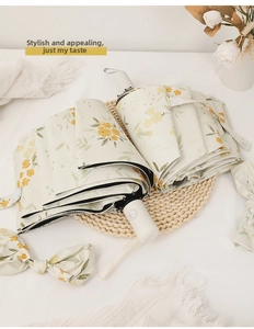 Detail of folding umbrella featuring cream floral print and matching bow accessory