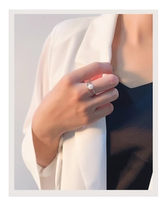 Macro detail of a silver double-layered crisscross ring featuring a white round pearl
