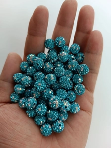 Close-up of sparkling lake blue disco ball clay beads with rhinestones held in hand