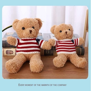 Detail of two brown teddy bears in red striped sweaters on books background