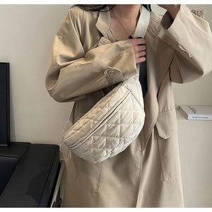 Detail of beige quilted nylon crossbody chest bag with adjustable wide strap on model