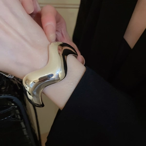 Dettaglio di un bracciale rigido a onde argento minimalista con finitura lucida