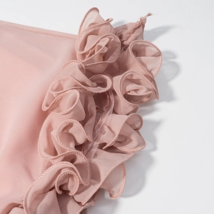 Detailed close-up of pink chiffon fabric with ruffled edges and pleat craftsmanship