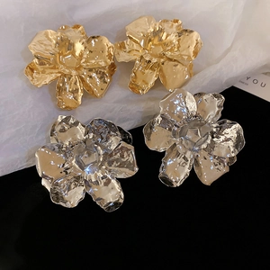 Detailed view of large metal flower earrings with hammered texture in gold and silver finish