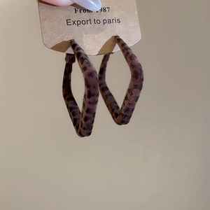 Gros plan de boucles d'oreilles créoles floquées léopard avec texture velours sur carte