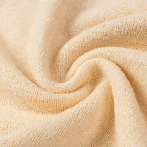 Vista macro del tessuto spugna beige con texture morbida e dettagli in maglia