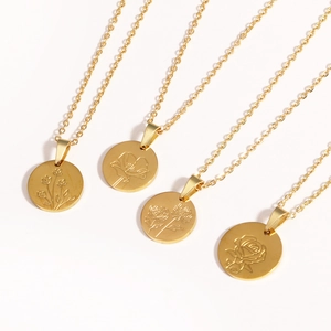 Detail of four golden titanium steel necklaces with circular floral engraved pendants