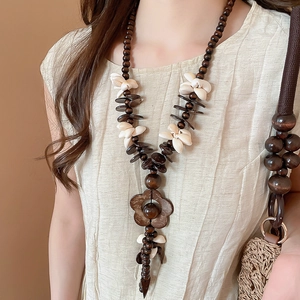 Detail einer Boho-Holzperlenkette mit Blumenanhänger an einem weiblichen Model