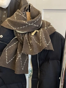 Detailed macro view of brown checkered knit scarf with wool-like texture and handmade label