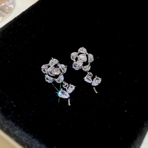 Vue macro des boucles d'oreilles fleur en argent et zircon avec breloque sur velours