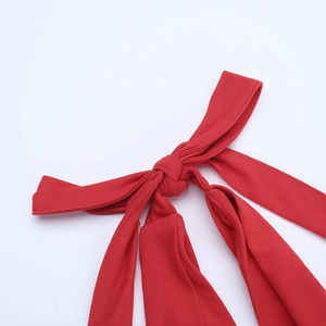 Close-up of the red backless bodysuit showing intricate knot details and premium stitching