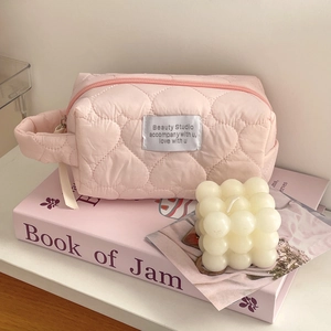 Detail of pink quilted heart makeup bag showing soft fabric texture and wide side handle