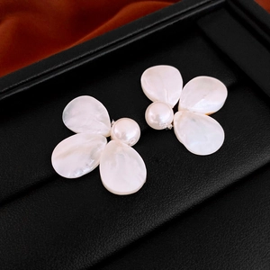 Close-up of elegant pearl flower earrings on a textured black leather jewelry display box