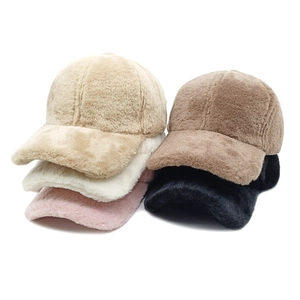 Dettaglio di cappellini da baseball invernali in peluche nei colori beige, bianco e nero