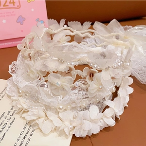 Detailed close-up of white lace floral headbands with elegant pearls and crystal accents