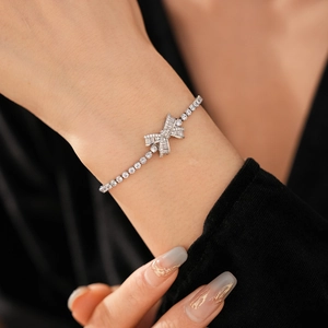 Close-up of sparkling zircon bow bracelet in silver on a wrist with black background