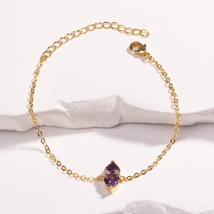 Detailed shot of double purple marquise stones on a delicate gold link chain bracelet