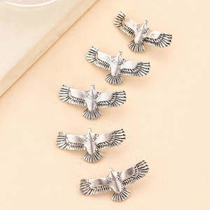 Detail view of five vintage silver eagle charms for DIY dreadlock hair accessories
