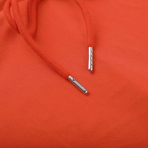 Macro shot of orange drawstring with polished silver metal tips on knitted fabric