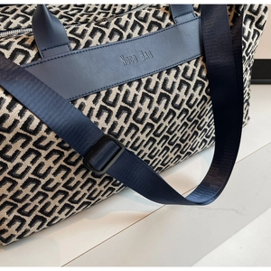 Détail rapproché du motif géométrique et de la sangle bleue d'un grand sac de voyage