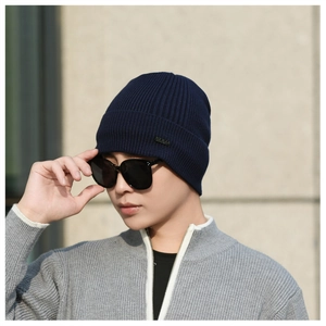 Close-up of navy blue ribbed knit beanie with a metallic logo plate for winter men