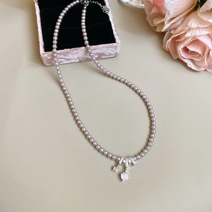 Détail d'un collier de perles avec pendentif argenté orné de pierres de zircone