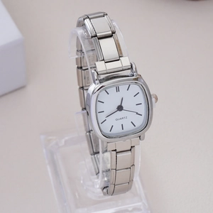 Detailed close-up of a square silver quartz watch with white dial on acrylic stand