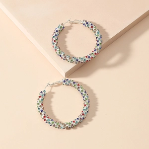 Macro shot of silver oversized hoop earrings featuring multi-colored rhinestone inlay