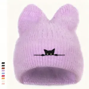 Detail der hellvioletten Plüsch-Strickmütze mit Katzenohren und Stickerei der Augen