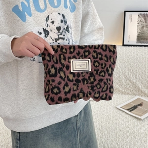 Handheld view of a leopard print plush pouch with a Pleasant Time woven label