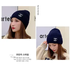 Close-up of navy blue ribbed knit beanie with a stylish MOMENT OF AMBITIONS square patch