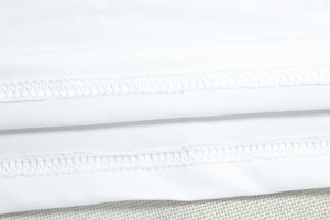 Detailed macro view of double-needle hem stitching on white knitted dress fabric